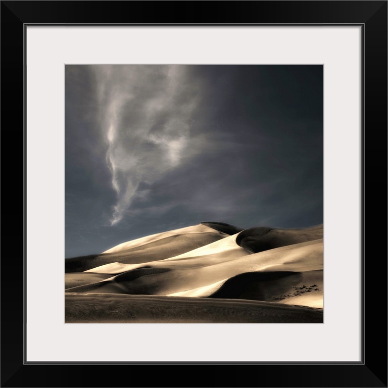 Desert sand dunes casting deep shadows under a darkening sky, Colorado.