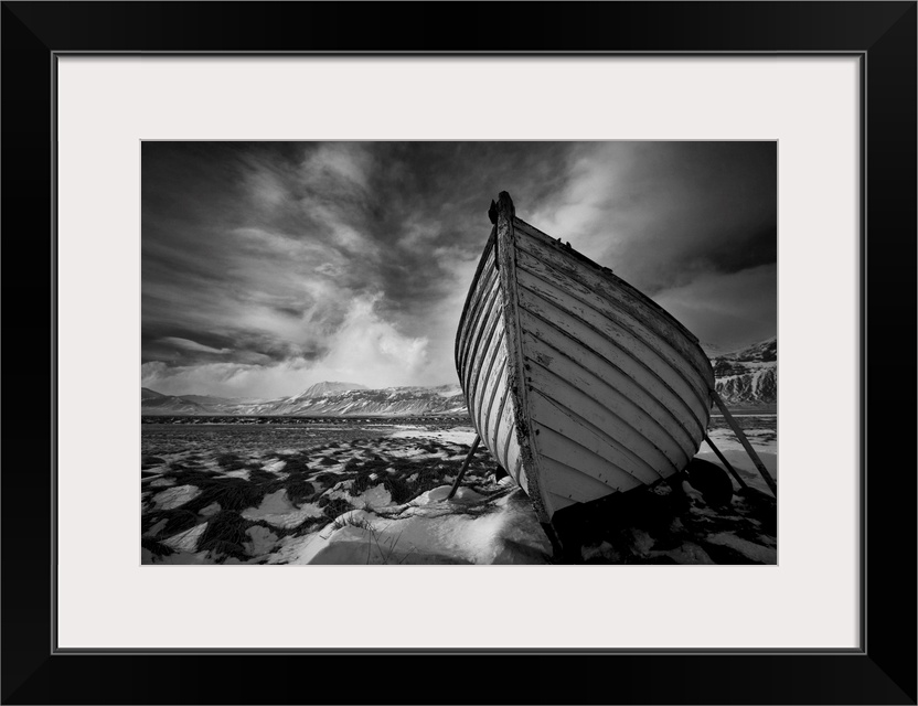 A black and white photograph of a row boat on the shore of an Icelandic beach.