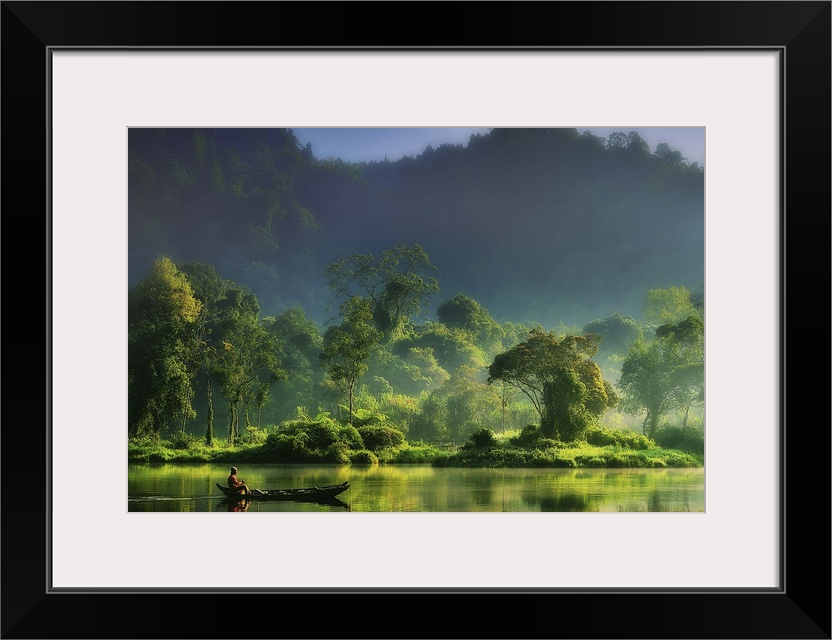 A figure on a boat in the middle of a river in the lush green Indonesian jungle.