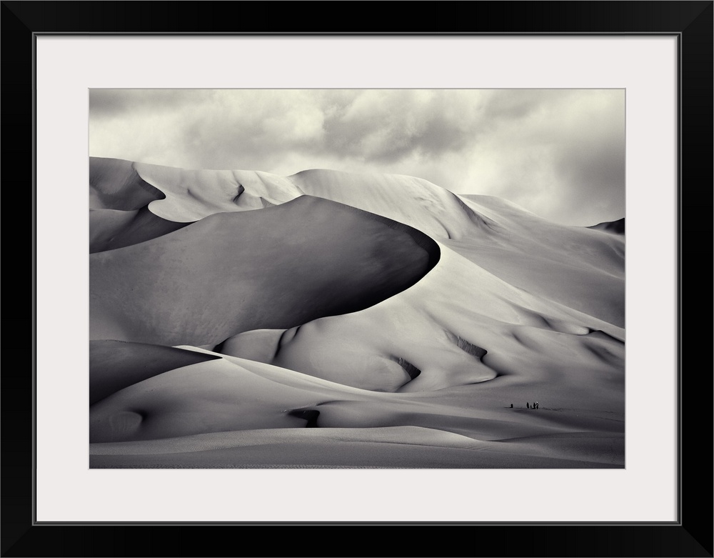 Gigantic sand dunes in the desert in Tenere, with tiny figures in the sand.