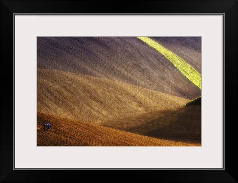 Three people run across dusty hills, with a streak of grass and power lines in the distance.