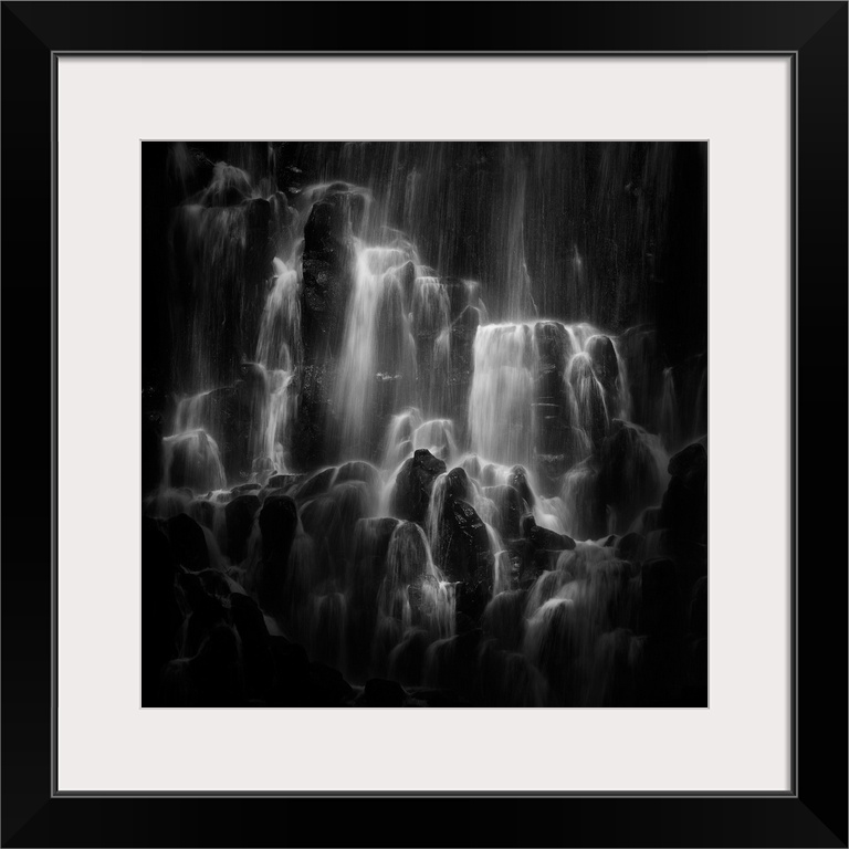 Water cascading down over top of jagged rocks.