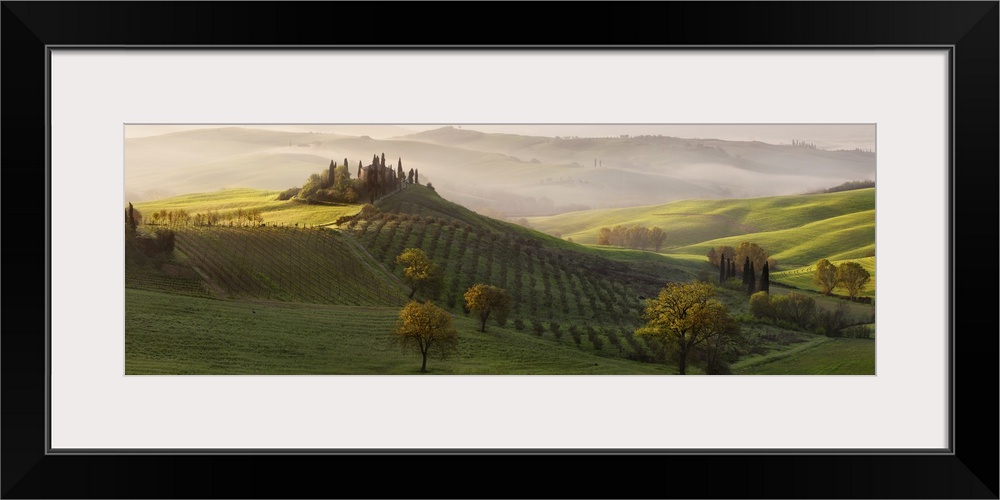 Tuscan countryside scene in early morning light with fog rolling in over the valley, Italy.