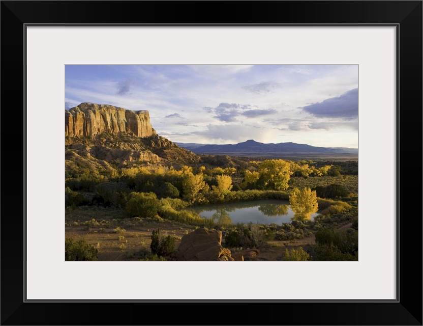 A pond is seen next to Kitchen Mesa with Pedernal Peak in the distance.