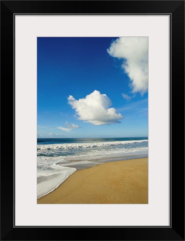 Atlantic ocean waves break on the beach on a sunny day with clouds.