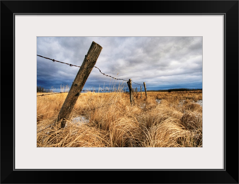 Barbed Wire Fence Posts With Dark Sky In Background, Alberta, Canada