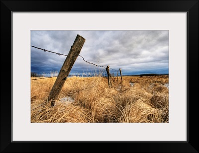 Barbed Wire Fence Posts With Dark Sky In Background, Alberta, Canada