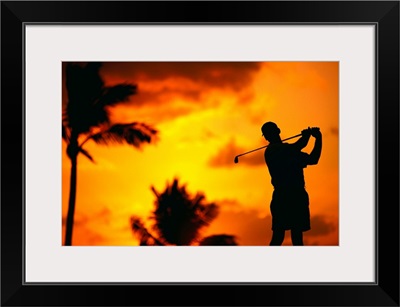 Close-Up Of Man Swinging, Silhouetted In Orange Skies, Palms Hazy In Background