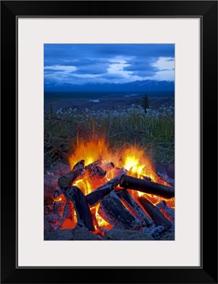 Close up view of a camp fire with a view of the Chugach Mountain in the distance