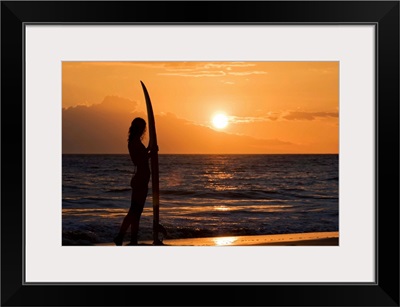 Hawaii, Female Surfer On Beach Silhouetted Against Orange Sunset Over Ocean