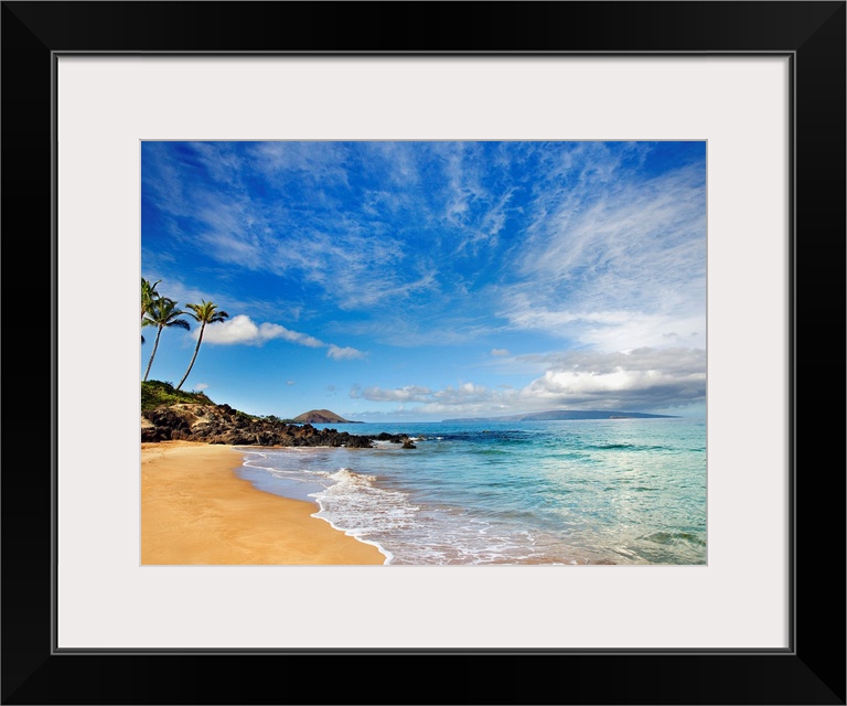 Tropical beach with small, calm waves under a partly cloudy sky, with a few palm trees in the distance.
