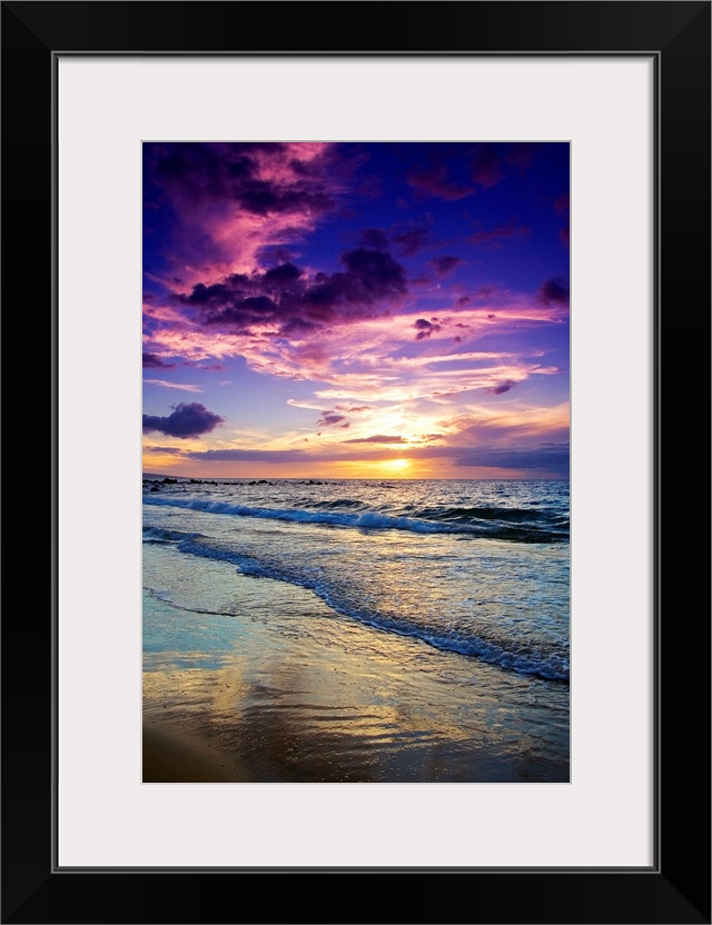 Large photograph displays the waves of the Pacific Ocean slowly coming into shore and crashing against the sandy beach of ...