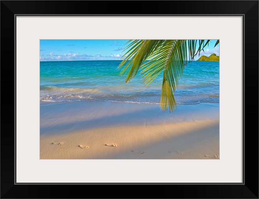 Panoramic photograph of shoreline with footprints in the sand.  There is a grass covered mountain in the distance and a pa...