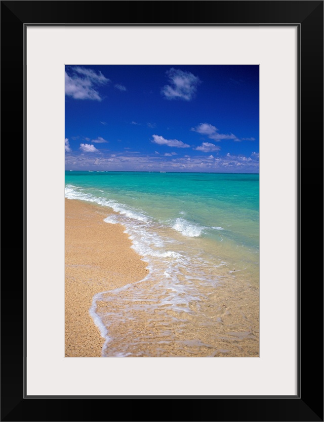 Shallow waters recede from the sandy coastline of a tropical beach, the clear sea stretching out into the distance.