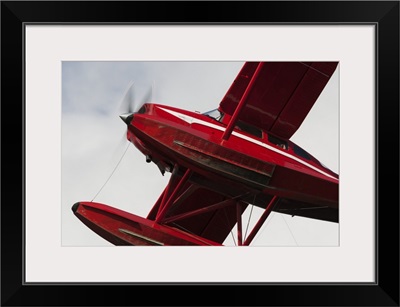 Low Angle View Of A Red Float Plane Against A Cloudy Sky; Alaska