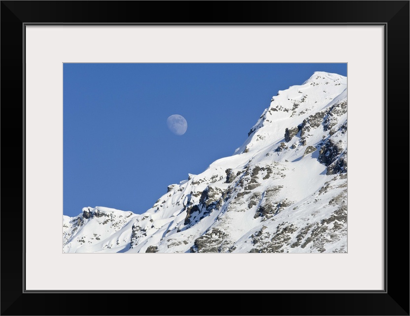 Moon rising over snow covered mountain peak at Hatcher Pass in Southcentral Alaska.