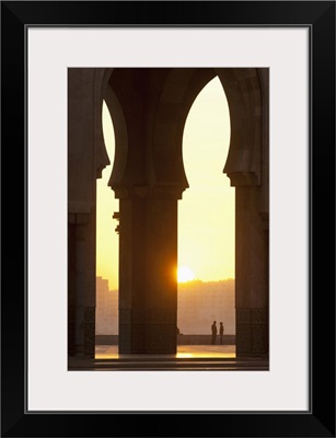 Morocco, Looking through arches of Hassan II mosque to couple chatting, Casablanca