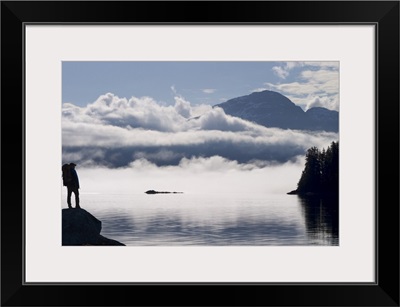 Silhouette of a backpacker along Lynn Canal near Juneau with Chilkat Mountains, Alaska