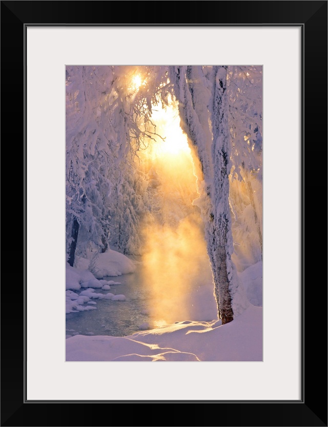 Photo of small stream runing through a hoarfrost covered forest, rays of sun filtering through the fog in the background, ...