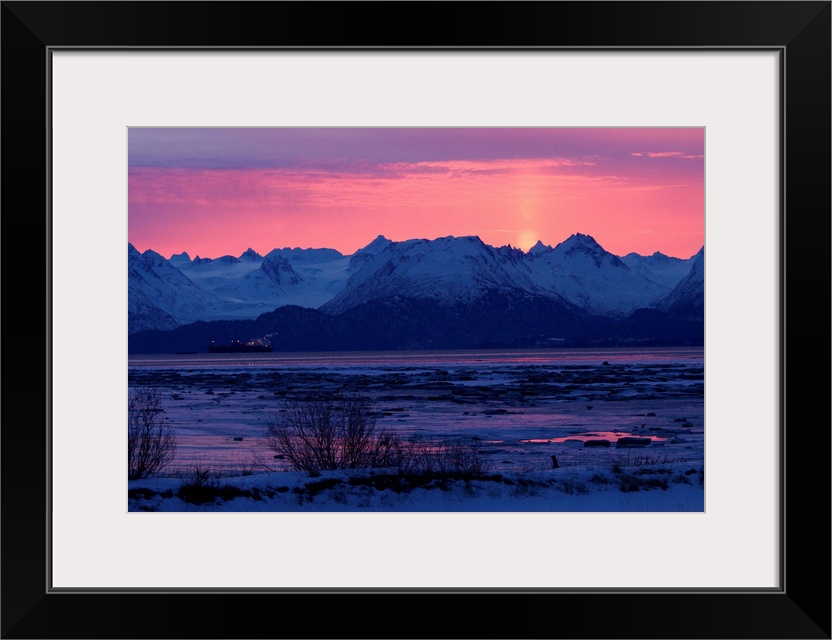 Photo print of rocky mountains with the sun setting behind them.