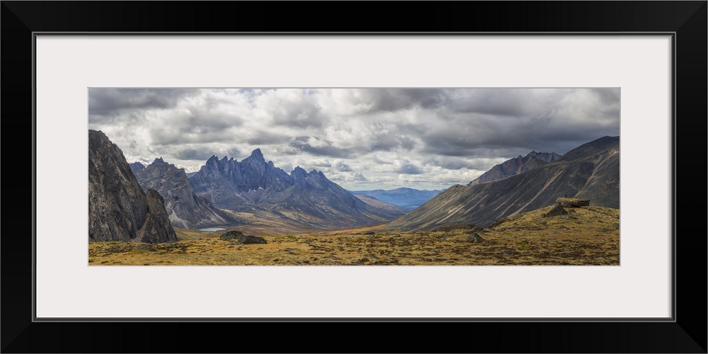 Men standing on a boulder in the distance in Tombstone Territorial Park in autumn. Yukon, Canada.