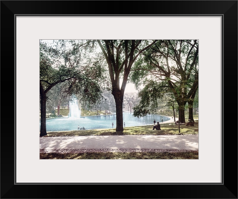 Vintage colored photograph of a pond in Boston Common Park with a spouting water feature in the middle of the pond and tre...