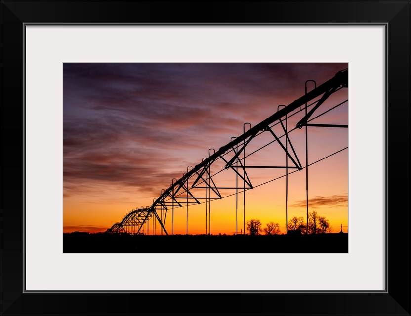 Beautiful sunset photograph with a silhouette of a farms irrigation system.