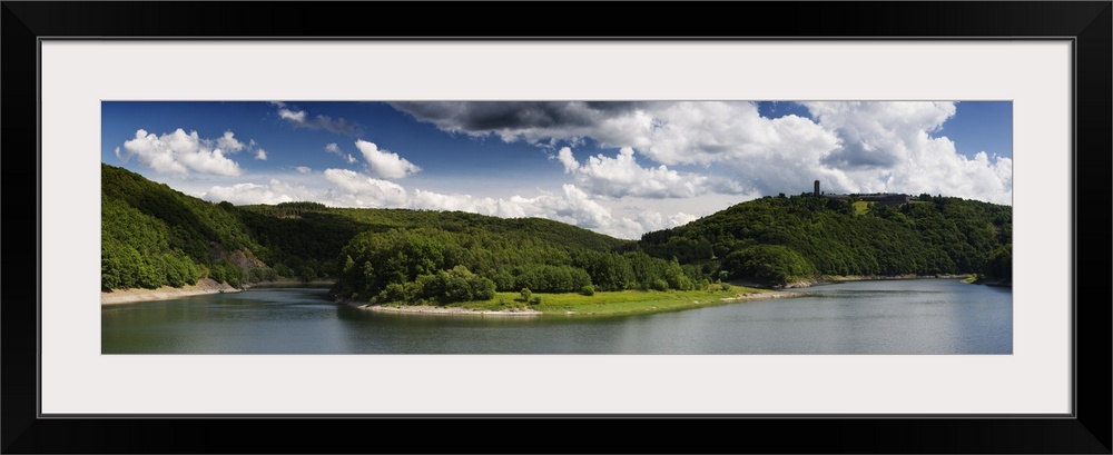 Panoramic photograph of a lake in the Eifel range in Germany under cloudy skies.