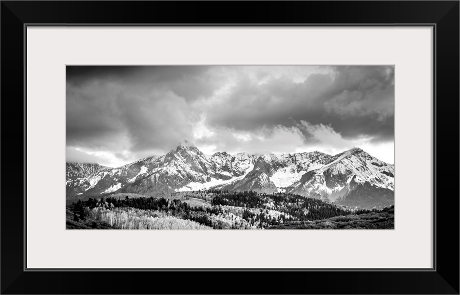 Black and white landscape photograph of snowy mountains under a cloudy sky.