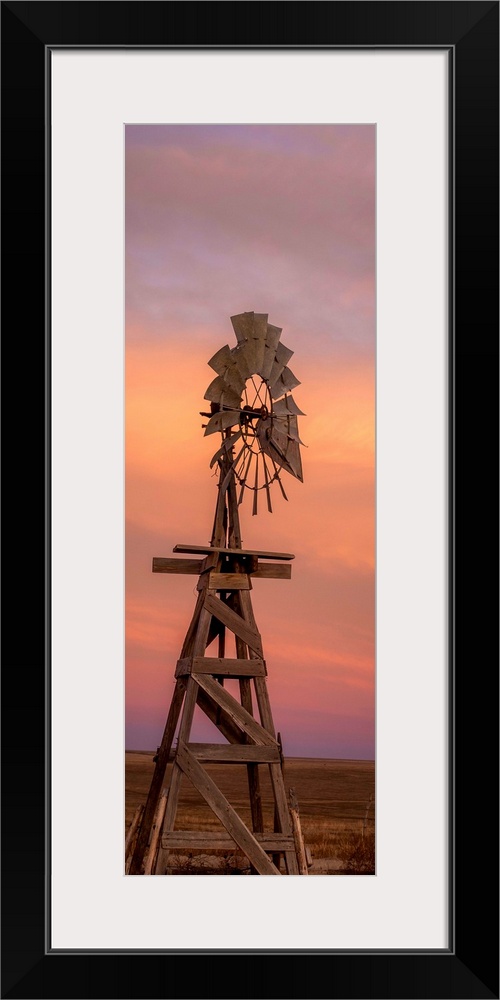 Tall photograph of a wooden windmill at sunset.