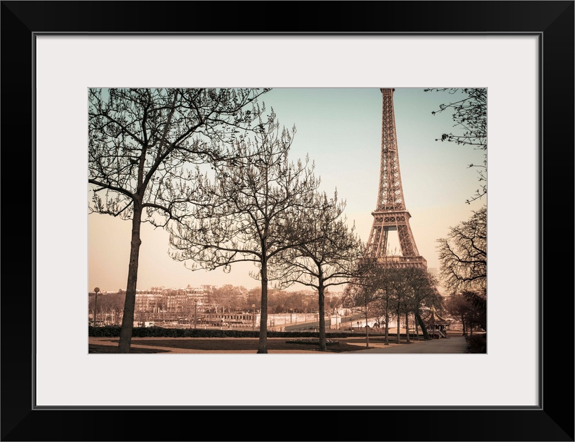 A muted colored photograph of the Eiffel Tower, viewed from a park sidewalk, in Paris, France.