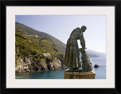Italy, A statue of St. Francis of Assisi petting a dog and looking out over the sea