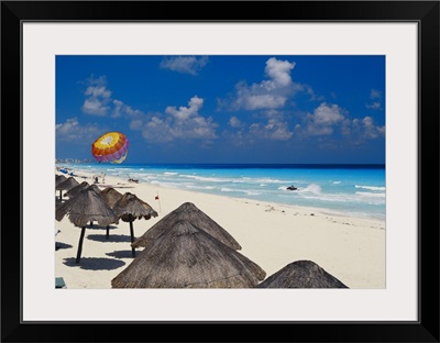 Mexico, Cancun, sunshades along beach with parachute in background