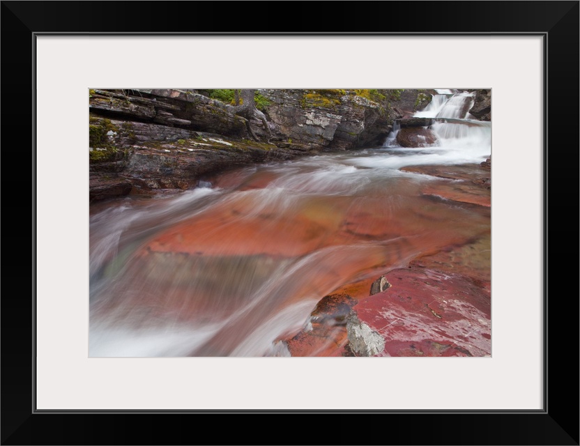 Water cascades down the red rock of Virginia Creek in Glacier National Park, Montana, USA