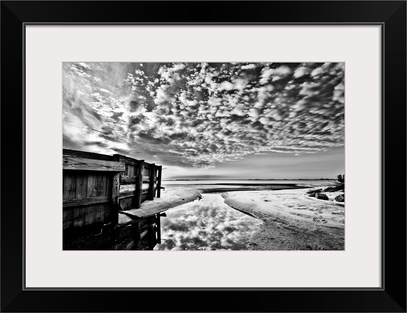 A black and white landscape with a wooden fence and popcorn clouds.