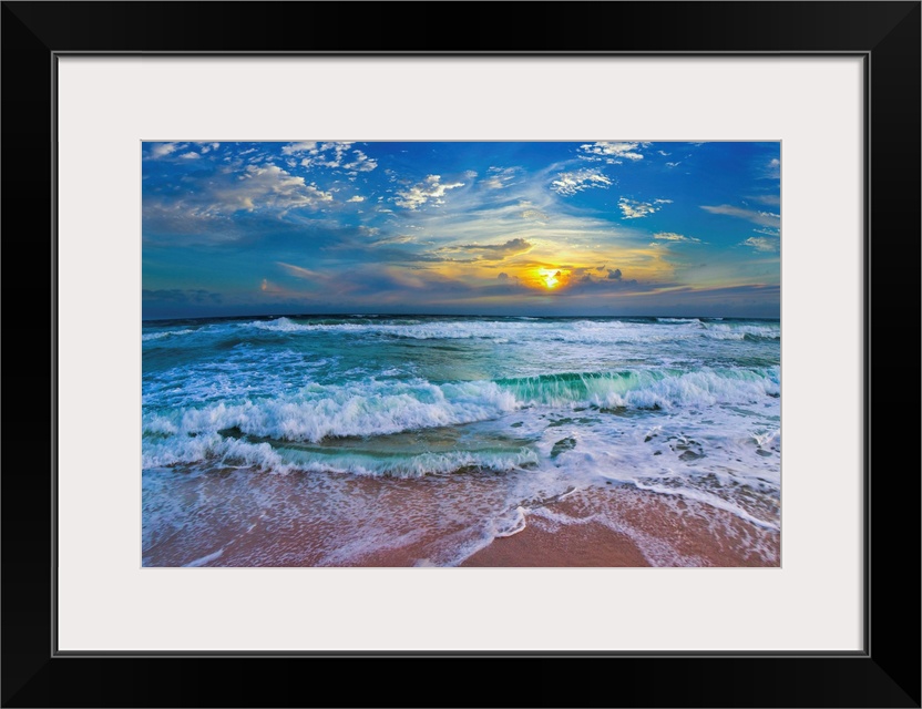 A glimpse of a yellow sunset within a cold blue sunset. Blue waves hit a tropical sea shore.