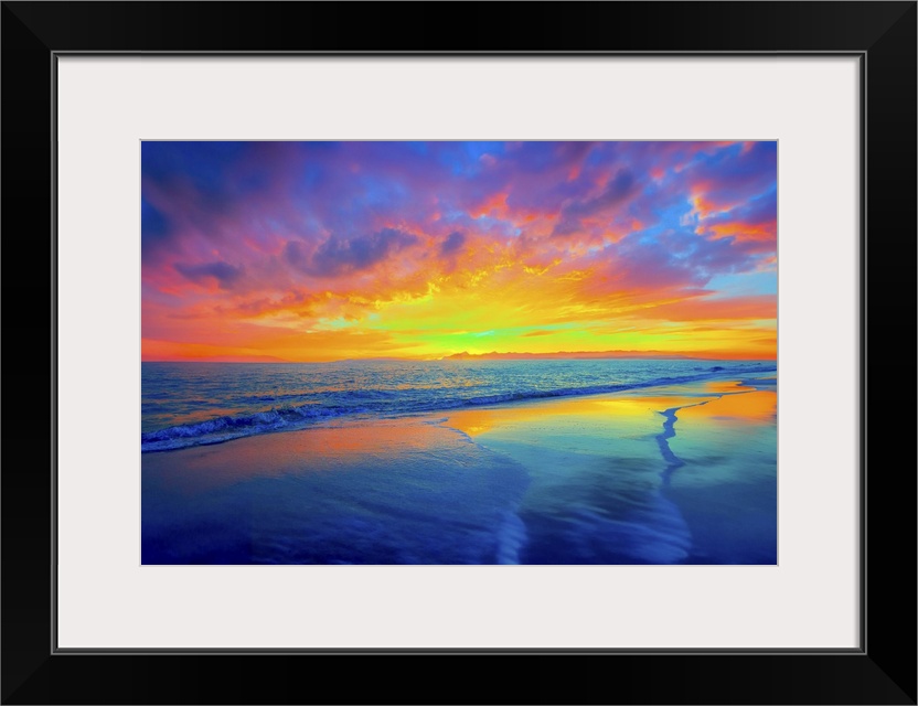 The pink and red twilight sky is reflected in the blue waters below. Waves caress the beach in this dreamy dark landscape.