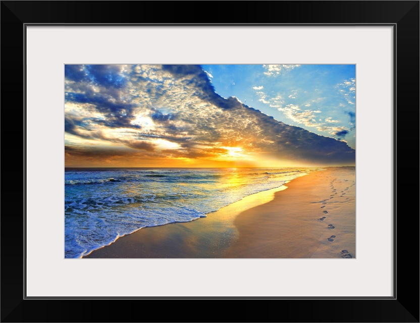 Bright golden sunset casts light onto the beach and blue seascape below. Landscape taken on Navarre Beach, Florida.