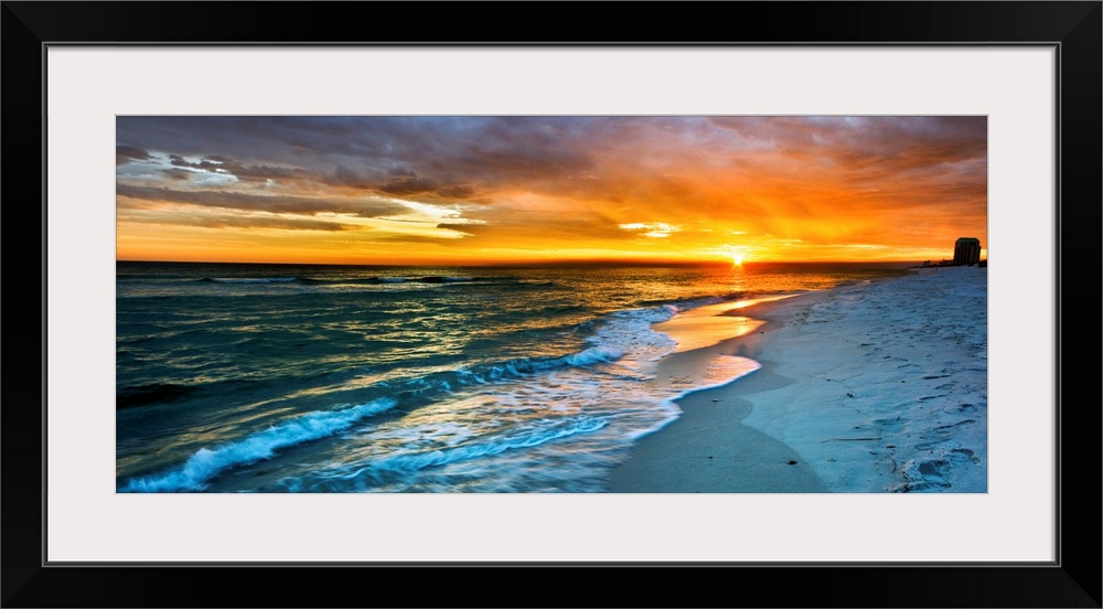 A dark beach before a panoramic orange sunset with a burning red sky. Landscape taken on Navarre Beach, Florida.