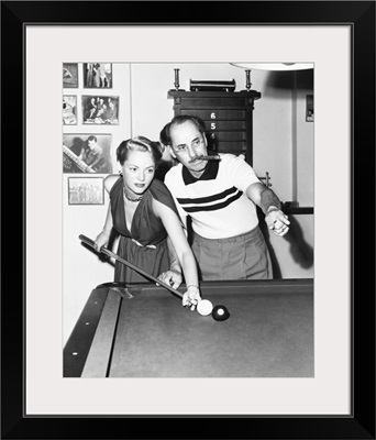 Groucho Marx at home playing billiards with his young wife, Actress Kay Maris
