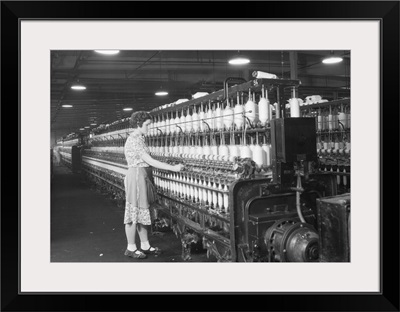 Woman standing at long row of bobbins, at a textile factory, Millville, NJ, 1936