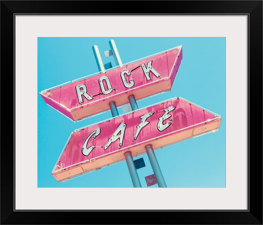 Photograph of a retro pink and white 'Rock Cafe' light up sign on a blue sky background.