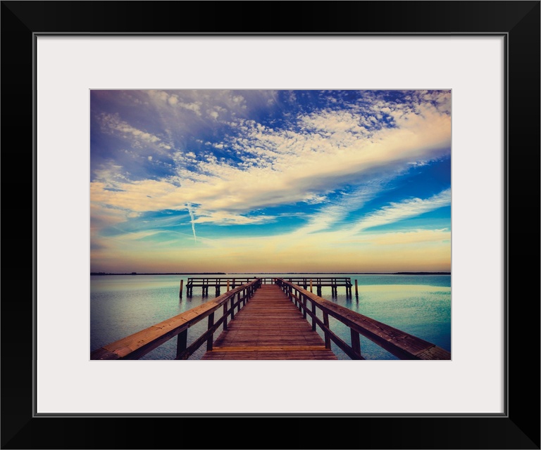 Photograph of a pier at sunrise with beautiful clouds.