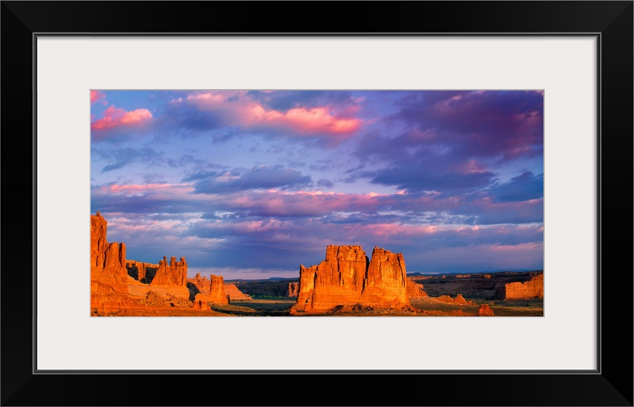 Tall rock formations illuminated at sunset in Arches National Park, Utah.