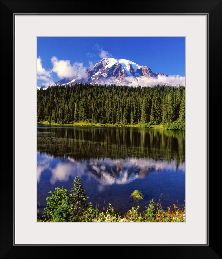 Mount Rainier surrounded by clouds seen from a lake.