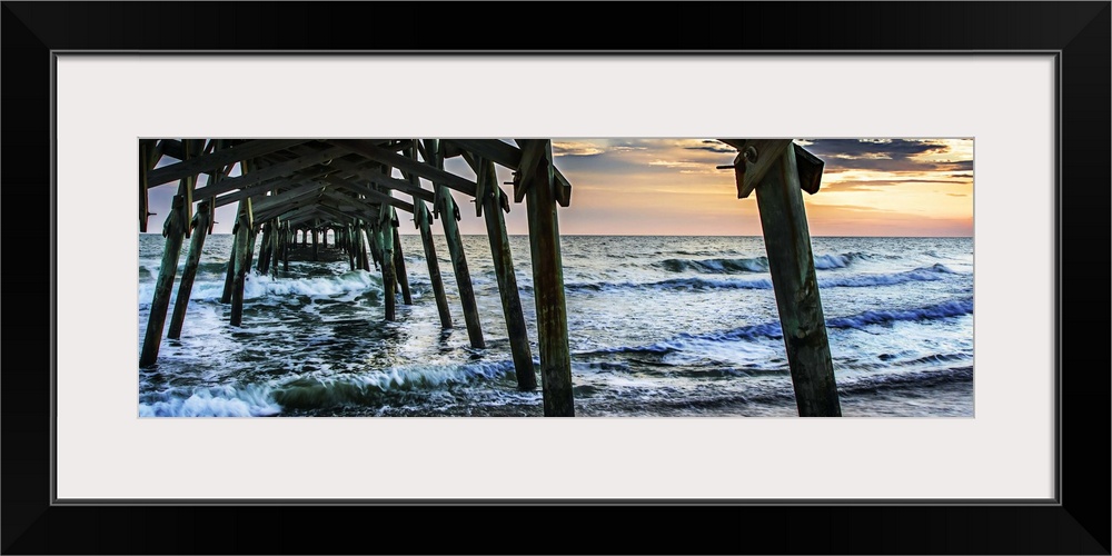 Wooden piers in the ocean silhouetted at sunset.