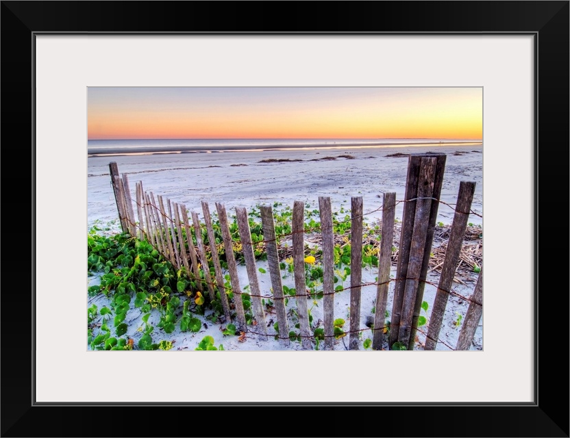 Wall art for the home or office this landscape photograph is of a battered barrier fence ends on the edge of the sandy sho...