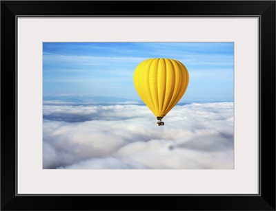 A Lonely Yellow Hot Air Balloon Floats Above The Clouds