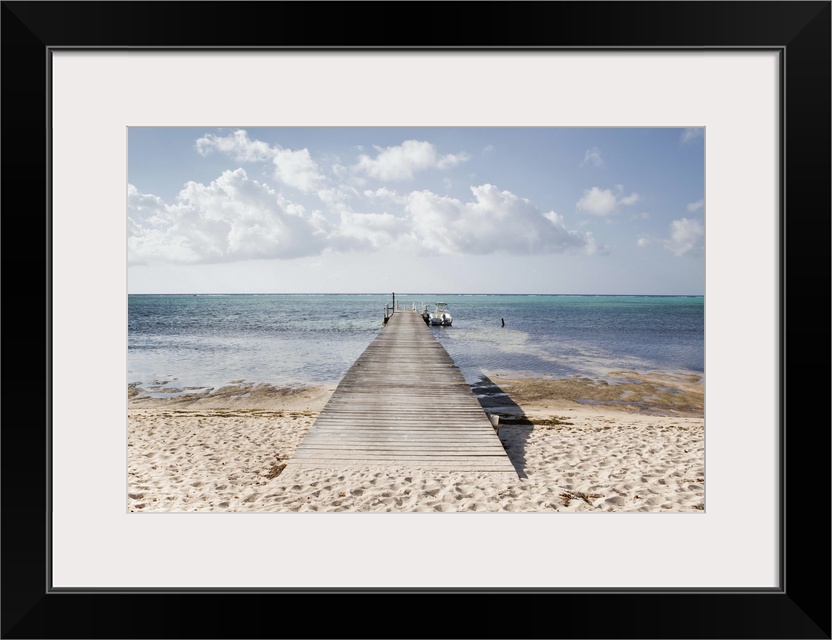 A long dock with a boat at the end stretches out into South Hole Sound on Little Cayman