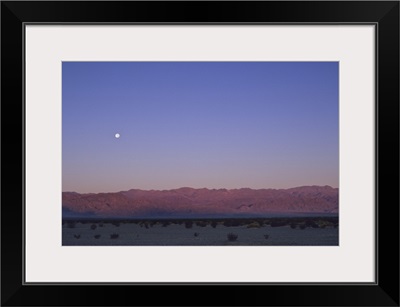 A moon above a mountain range in Death Valley National Park